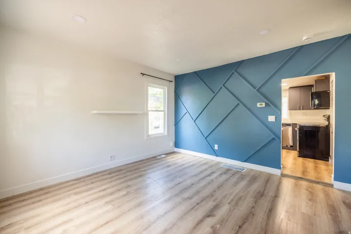 Wood-finish flooring throughout, featuring a geometric accent wall and recessed lighting