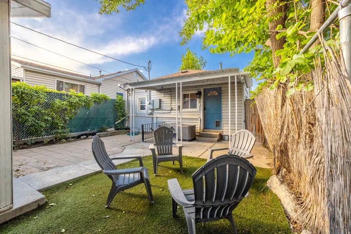 Backyard featuring artificial turf, a paved patio, and mature trees