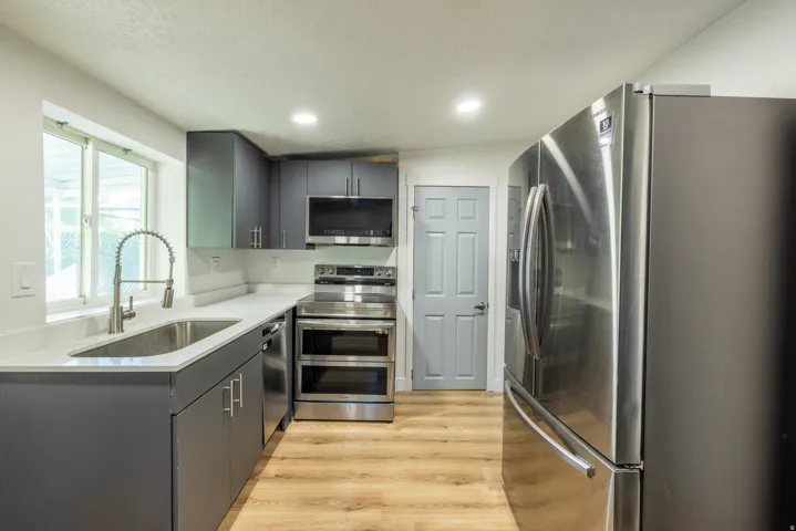 Kitchen featuring stainless steel appliances, wood-finish flooring, recessed lighting, gray cabinetry, and white countertops