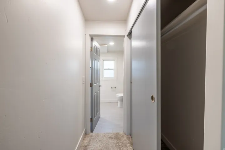 Hallway with light-toned walls, recessed lighting, and a sliding closet door
