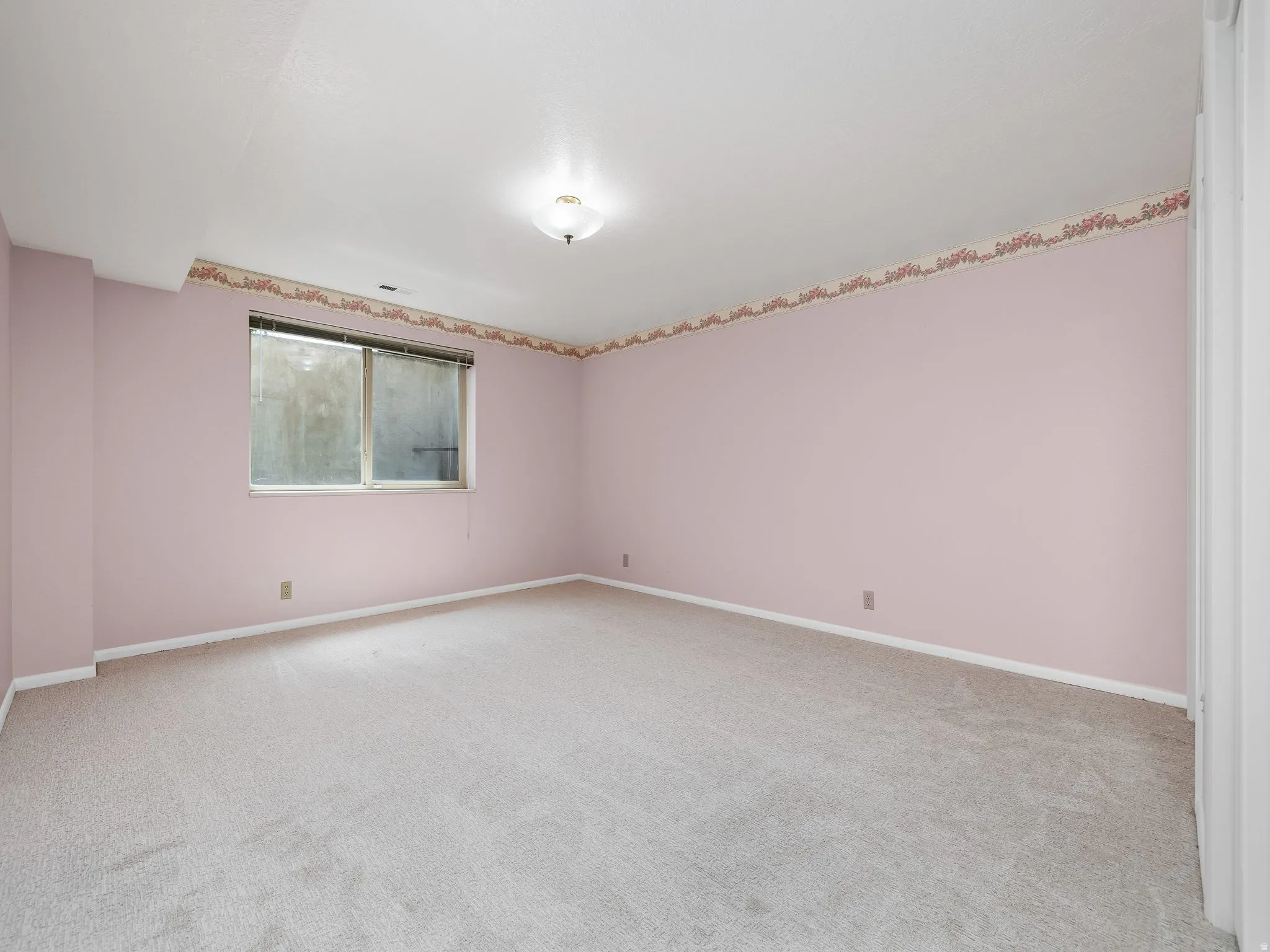 Recessed window, ceiling-mounted light fixture, light-toned carpeting, and painted walls