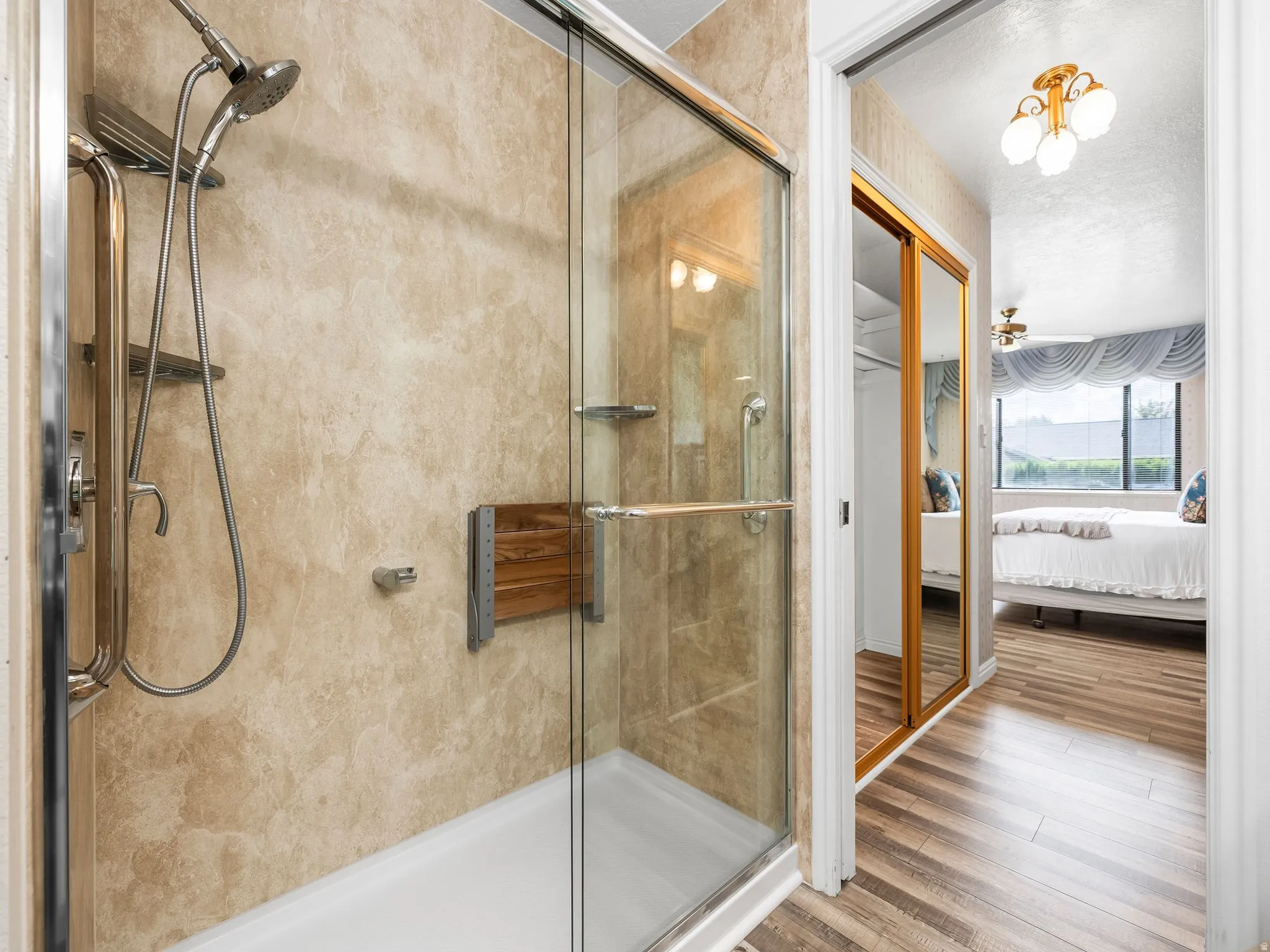 Walk-in shower with glass enclosure, textured wall paneling, and a built-in shower seat