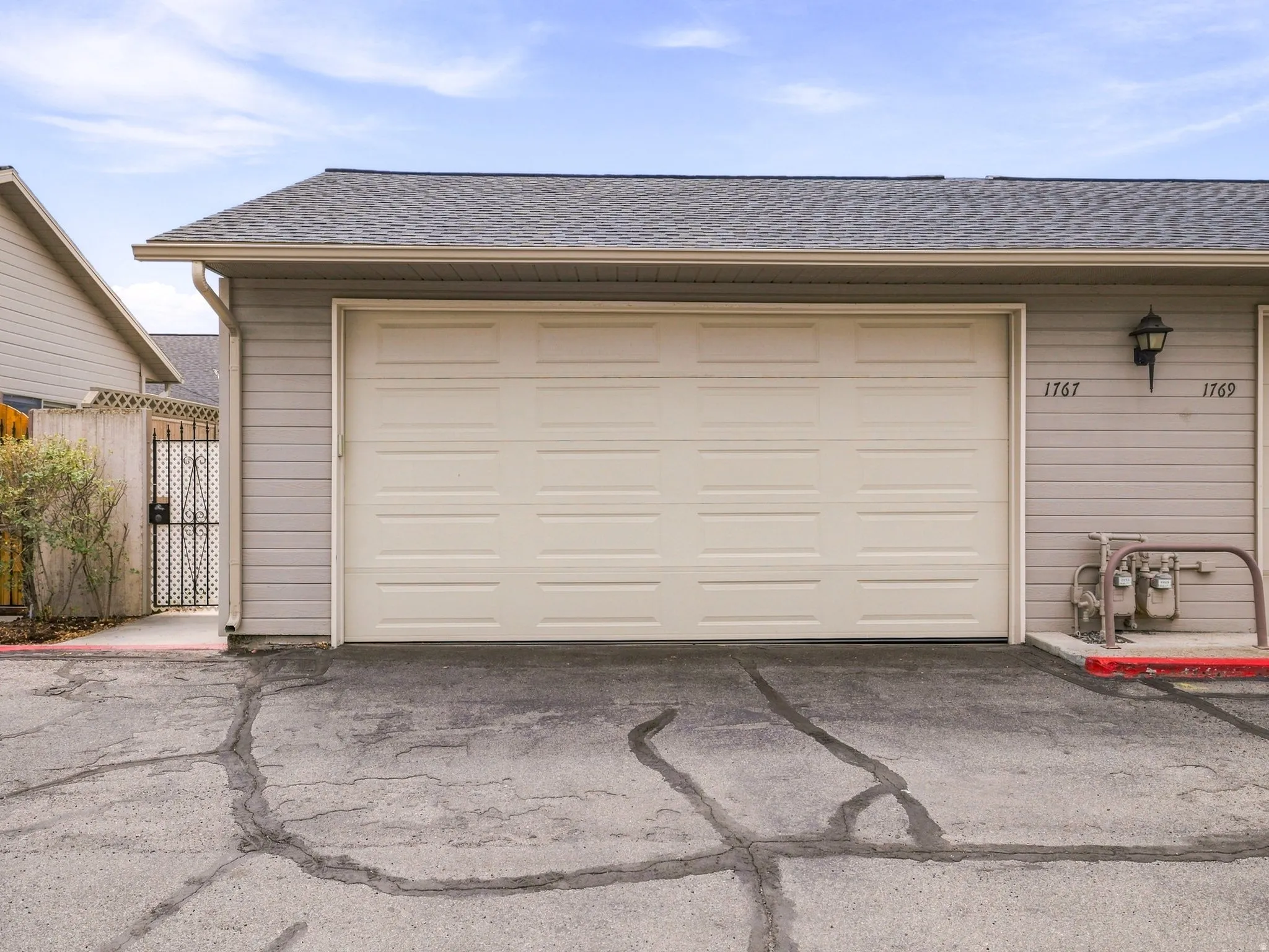 Attached garage with panel door, gray shingle roof, and light-colored siding