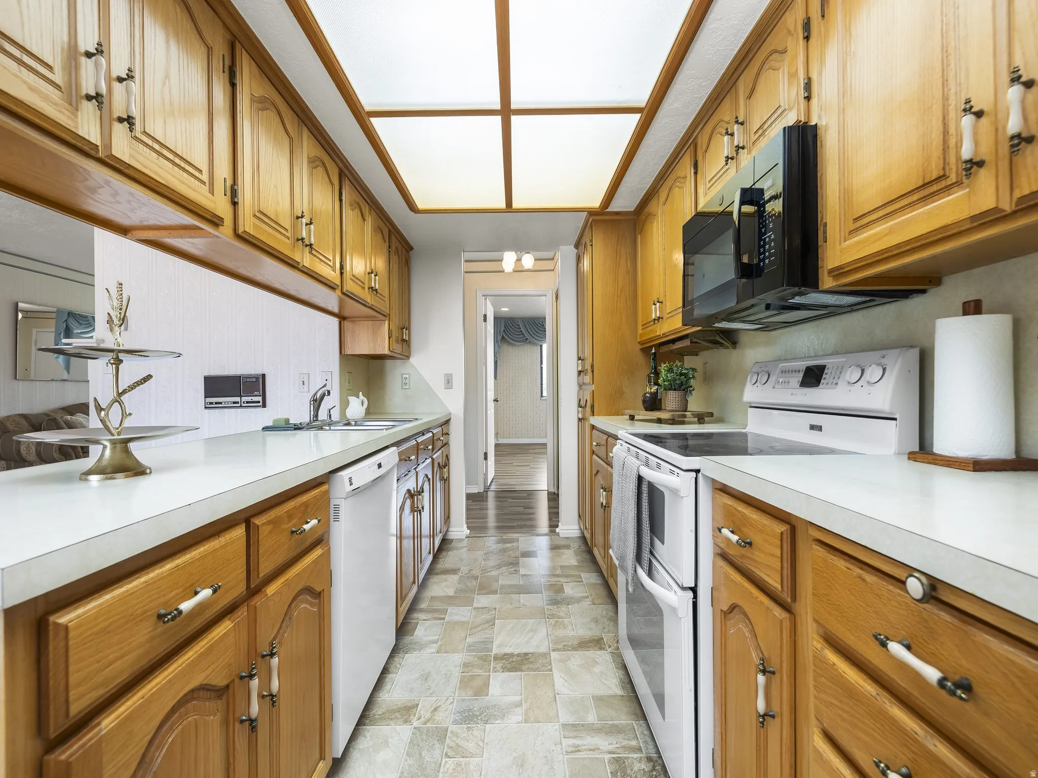 Galley kitchen featuring wood cabinetry, white countertops, built-in microwave, and oven with cooktop