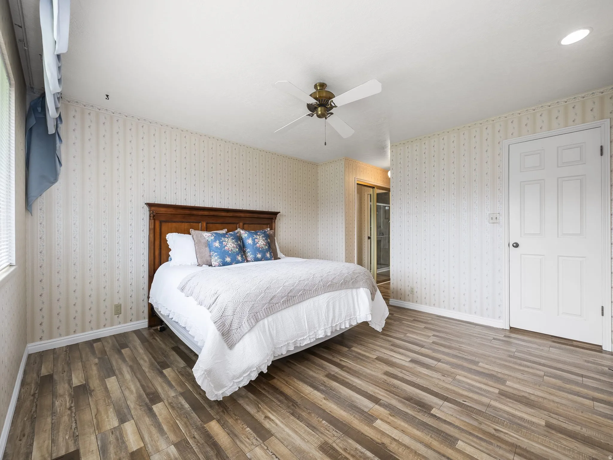 Wood-finish flooring throughout, ceiling fan with light fixture, and a solid wood headboard