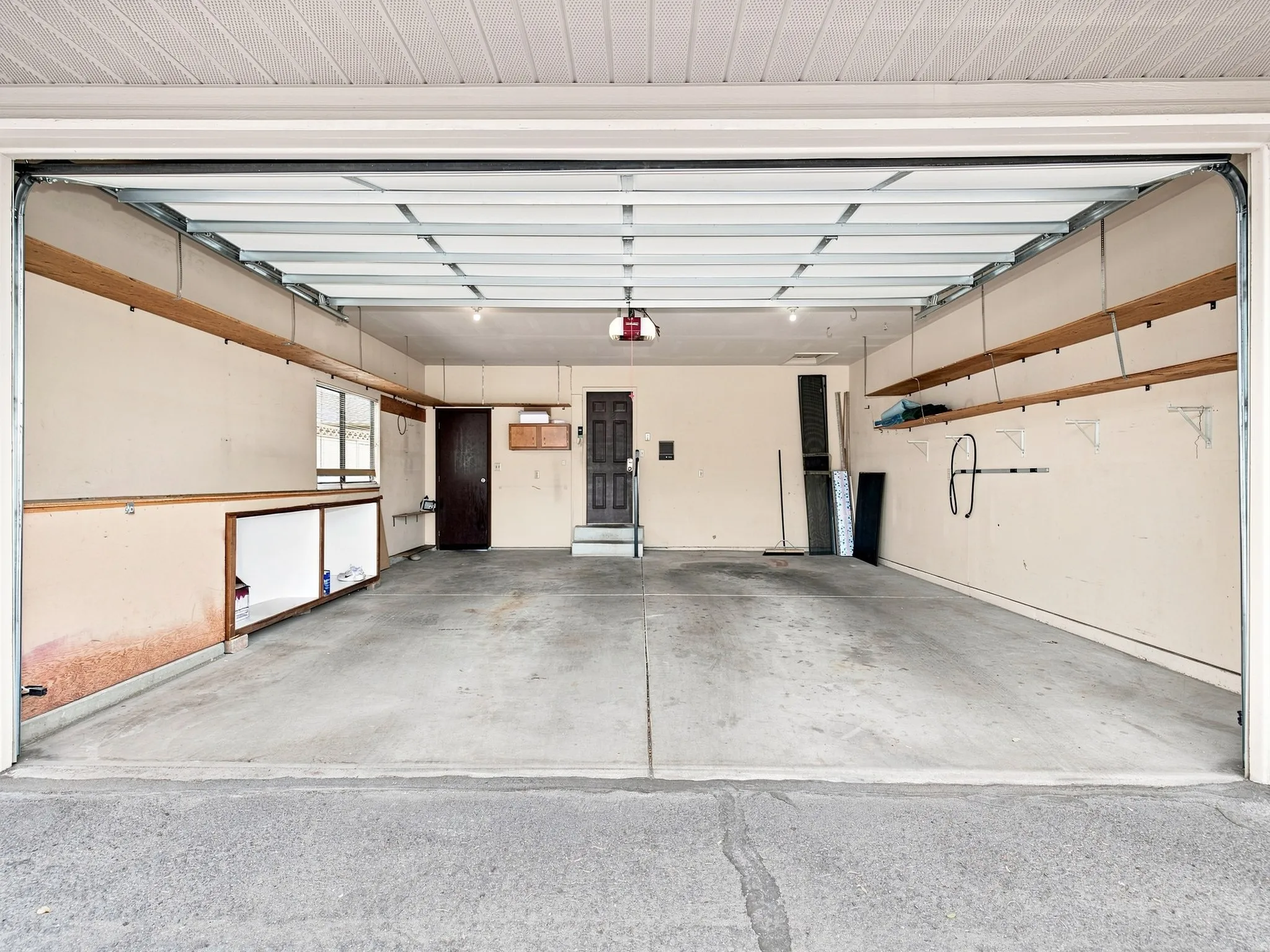 Spacious garage featuring concrete flooring, built-in shelving, overhead lighting, and a utility window