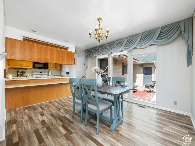 Hardwood-finish flooring, brass chandelier, wood cabinetry, built-in microwave, and sliding glass door