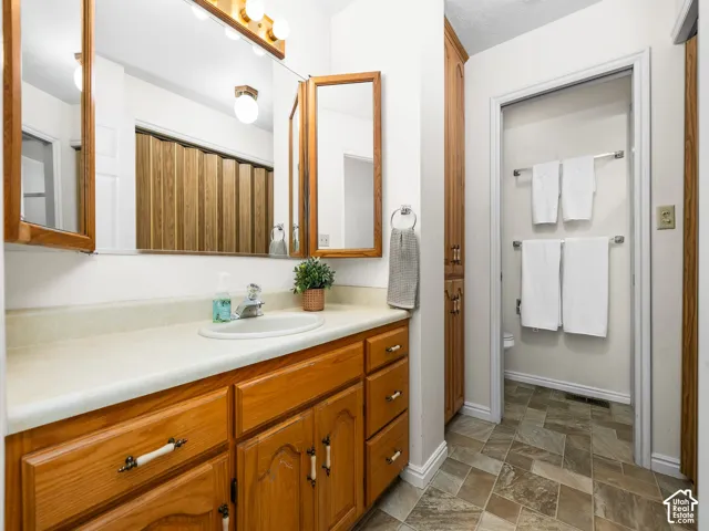 Bathroom vanity with wood-finish cabinetry, a drop-in sink, and a light-toned countertop