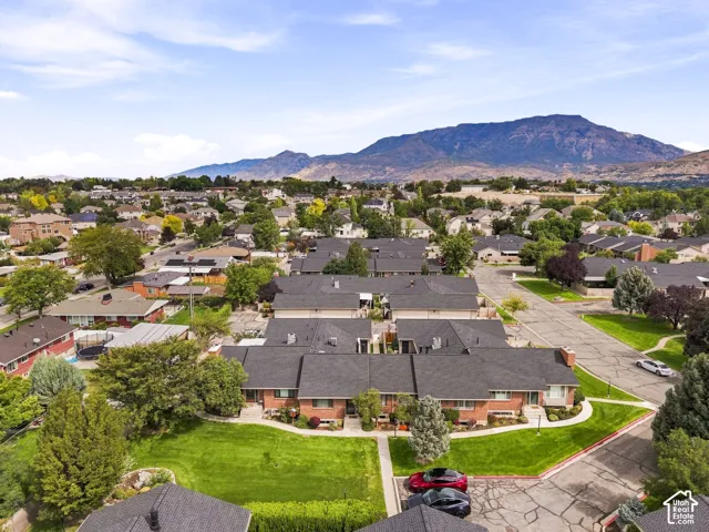 Expansive suburban neighborhood with mountain scenery, featuring a collection of brick properties with dark shingle roofs, and mature landscaping