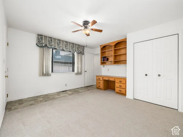 Built-in desk with shelving, ceiling fan, and bi-fold closet doors