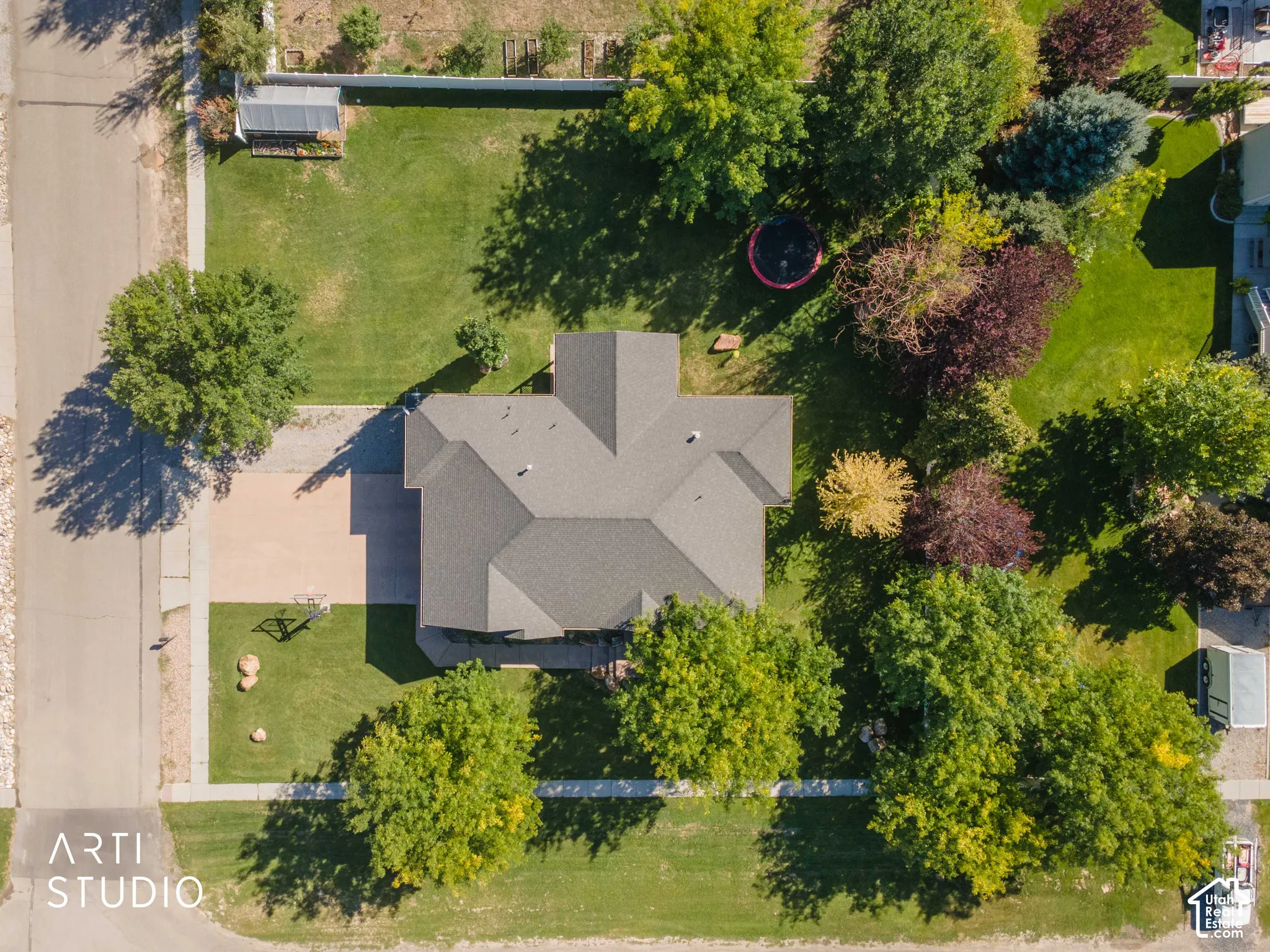 Property with a gray asphalt shingle roof, paved driveway, and established landscaping