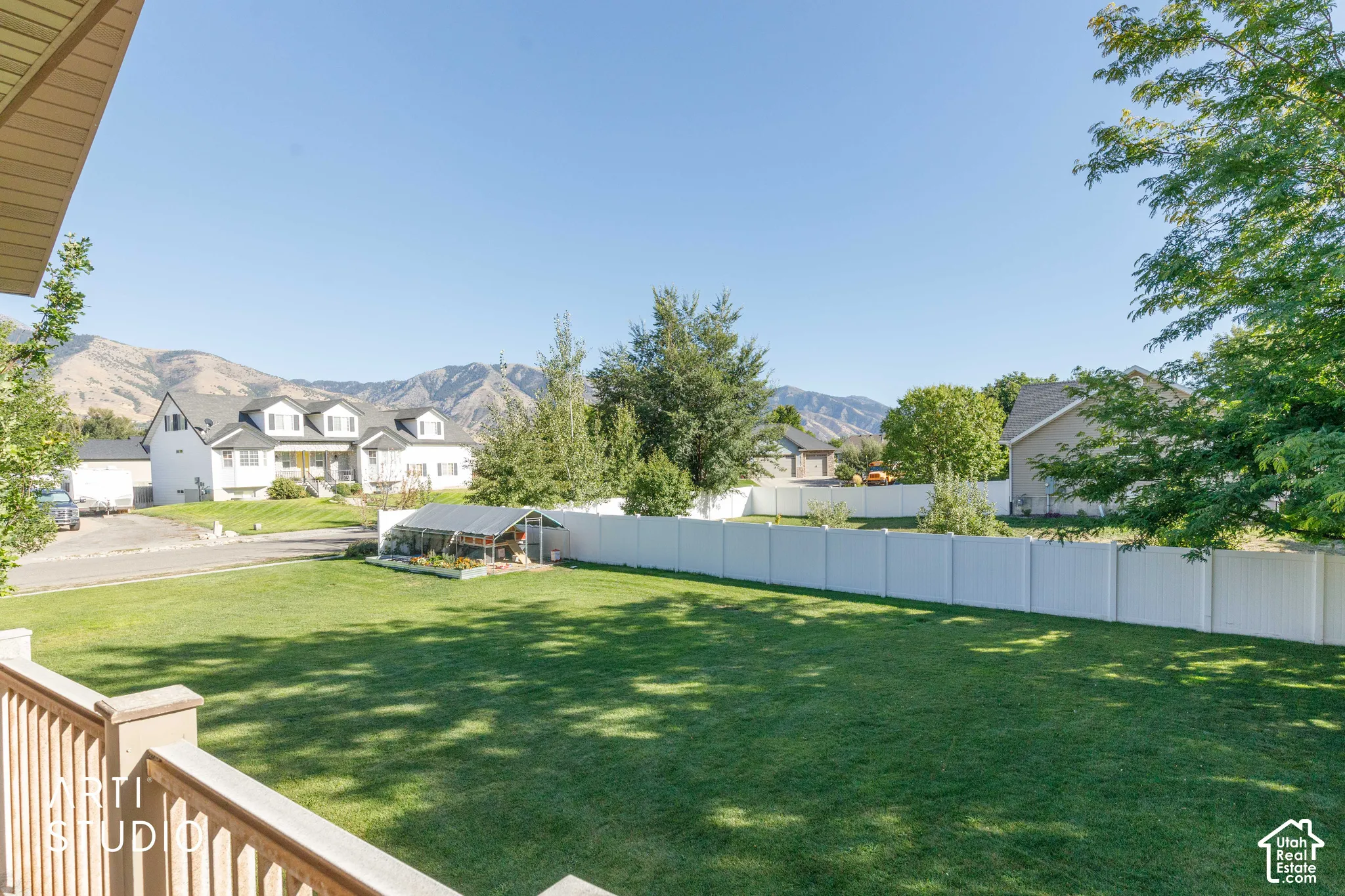 Expansive backyard featuring a manicured lawn, established trees, and a white privacy fence