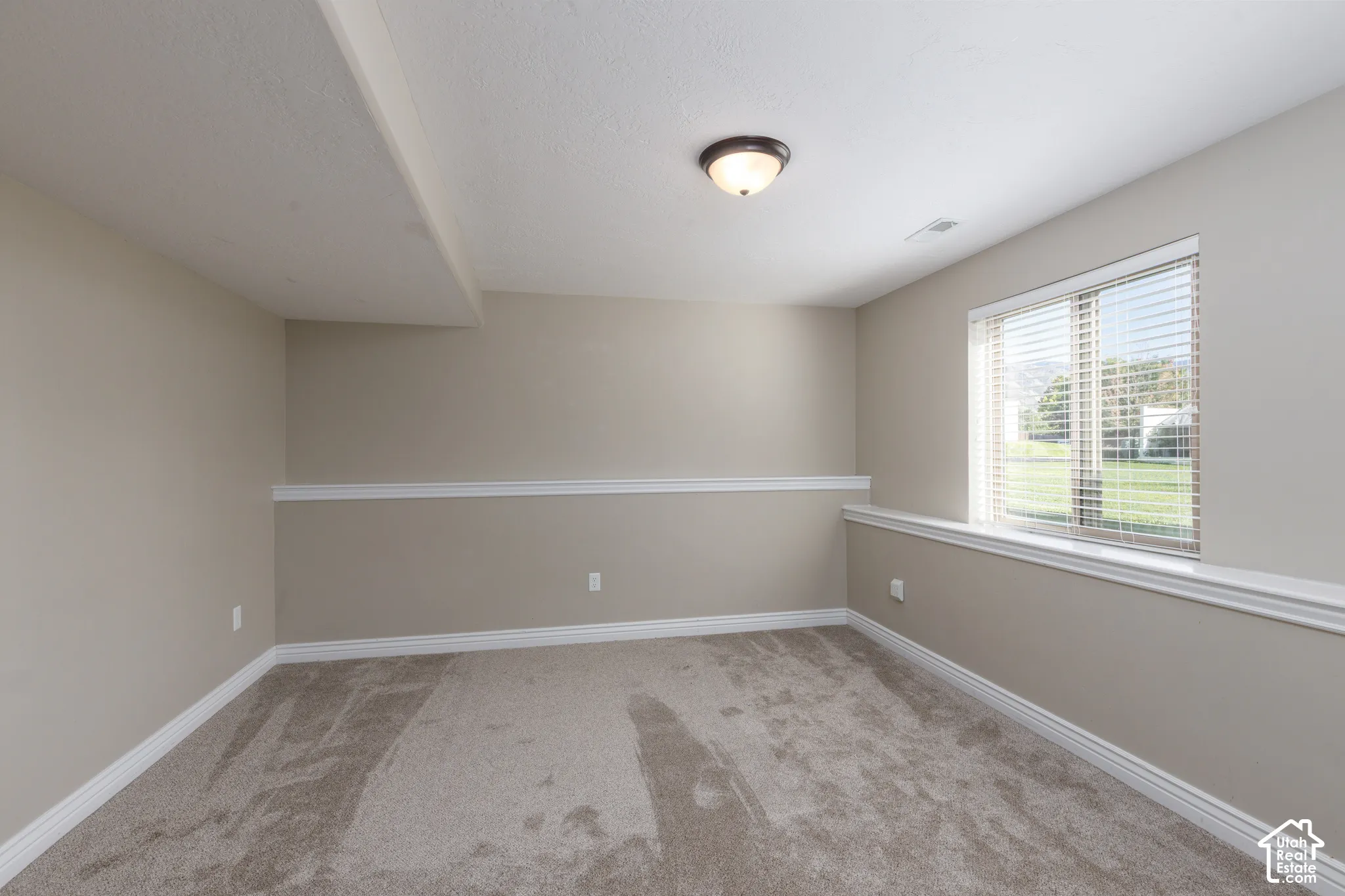 Neutral-toned walls with chair rail molding and plush carpet flooring