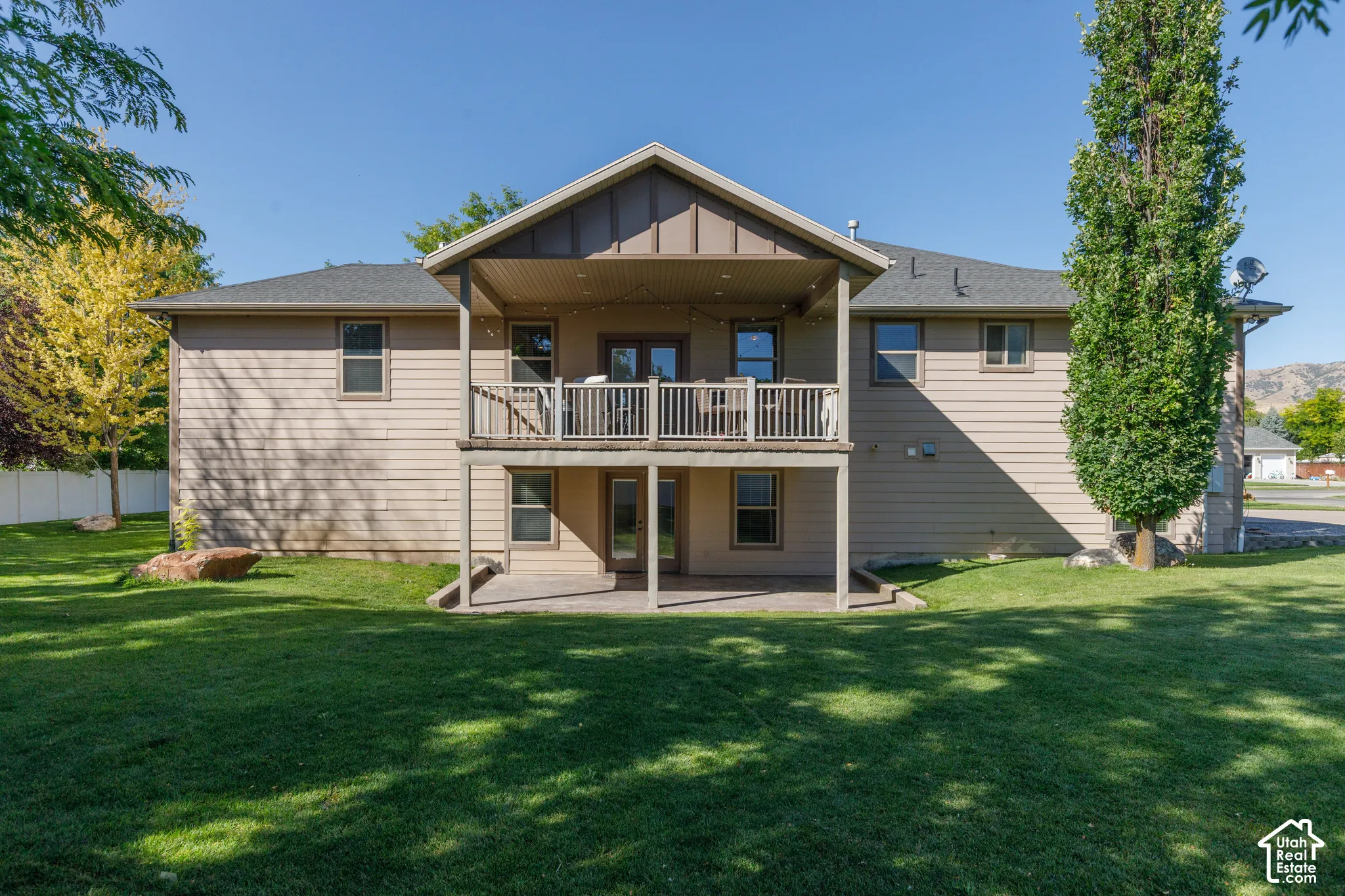 Expansive backyard with a covered upper deck, lower patio, and mature trees