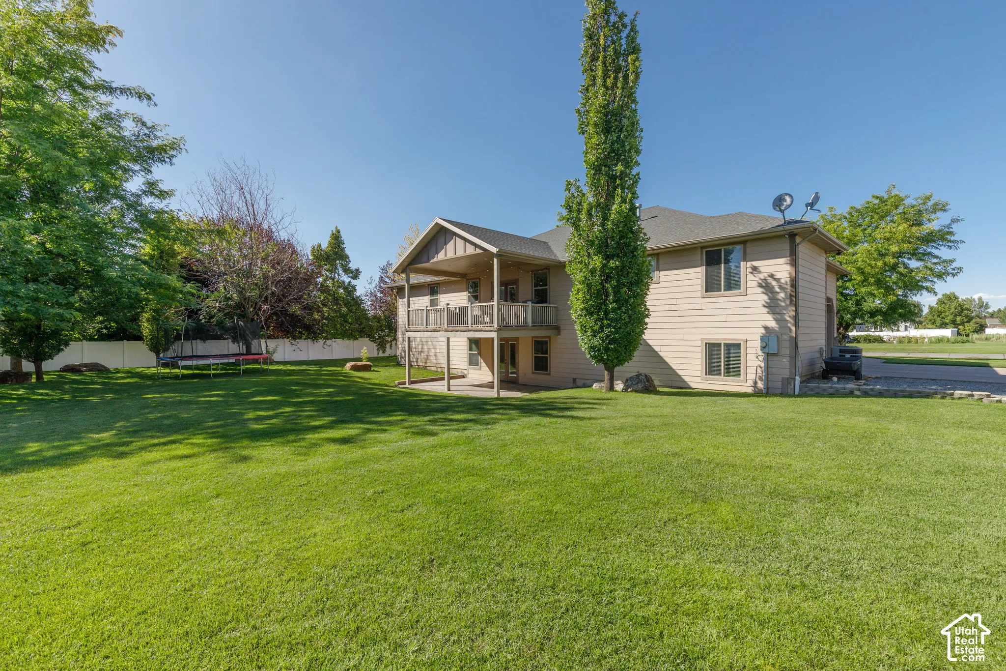 Expansive green lawn with mature trees and a privacy fence