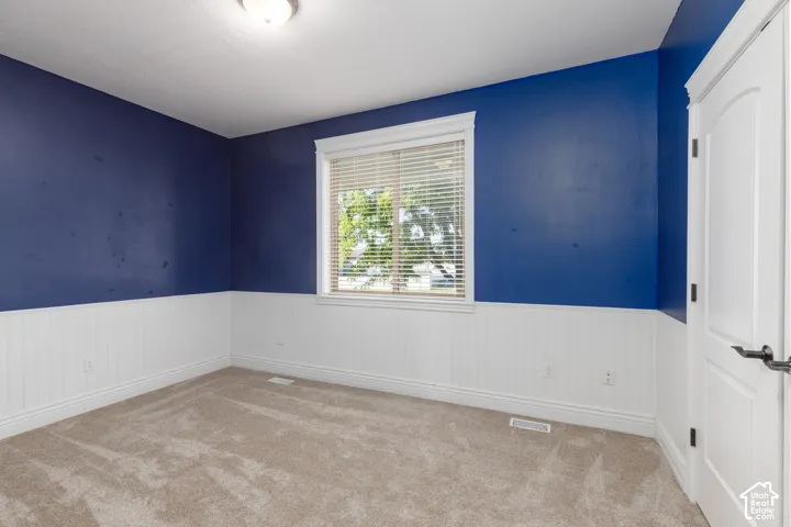 Wall-to-wall carpeting, window with blinds, beadboard wainscoting, and a panel door with dark hardware