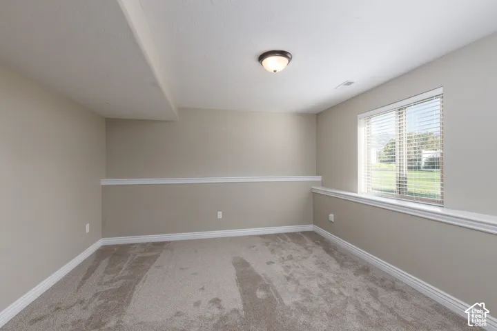 Neutral-toned walls with chair rail molding and plush carpet flooring