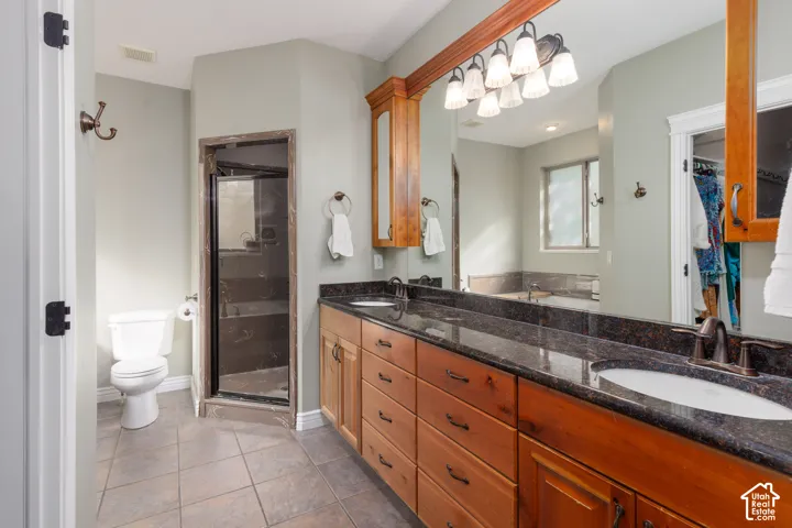 Dual vanity with dark stone countertop, wood-finish cabinetry, and framed mirror