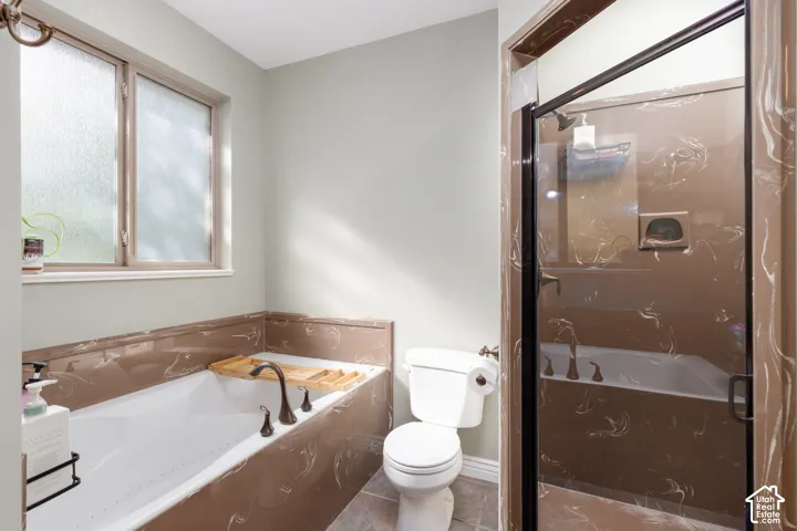 Porcelain bathtub with bronze-finish fixtures, a frosted window, and a shower with a clear glass enclosure and bronze-finish trim