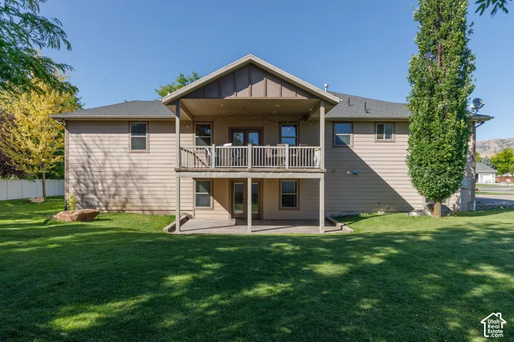 Expansive backyard with a covered upper deck, lower patio, and mature trees