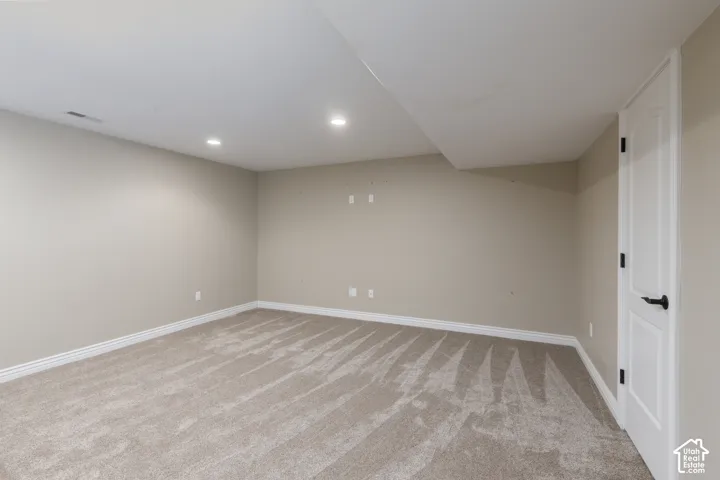 Recessed lighting illuminates neutral-toned carpeting and walls