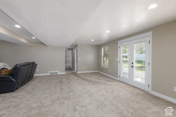 Recessed lighting, neutral wall paint, light-colored carpeting, white trim, and a glass-paned double door