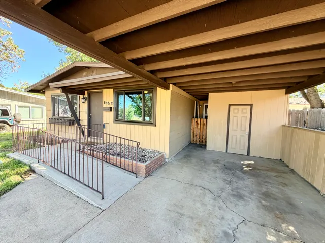 Covered carport entry featuring a concrete slab and a panel door storage area