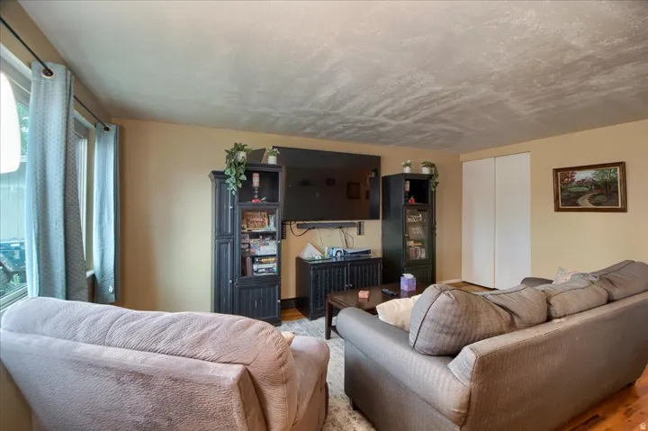 Recessed lighting with a textured ceiling, neutral wall paint, and natural light from a window