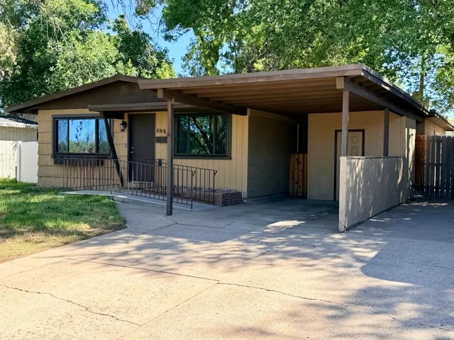 Covered carport, front entry ramp, exterior siding, metal handrails, and a concrete driveway