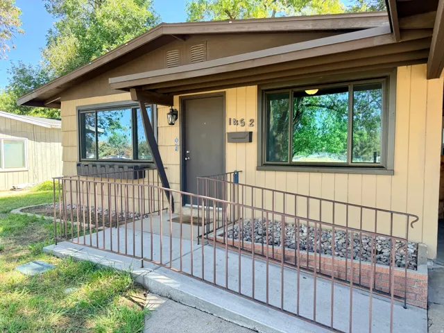 Front entry with a concrete accessibility ramp and metal railing