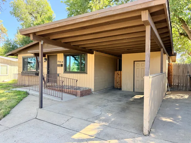 Carport with exposed wood beam construction, concrete driveway, and covered entry