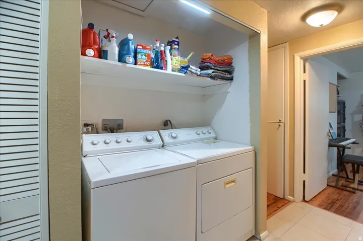 Dedicated laundry area with built-in shelving and louvered bifold doors