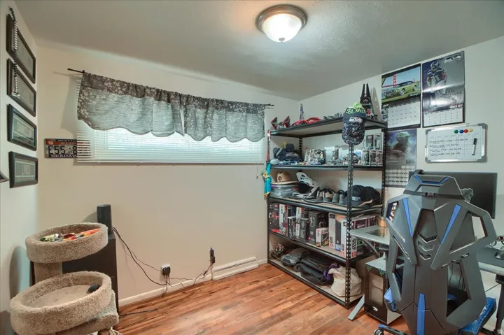 Wood-finish flooring with neutral wall paint and a single window featuring blinds