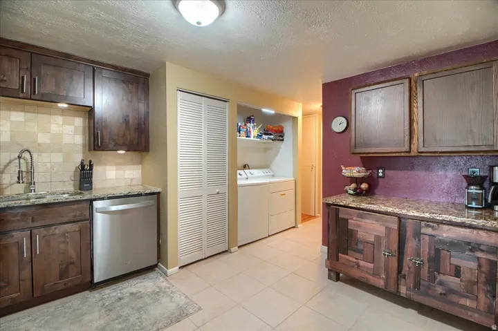 Kitchen featuring wood cabinetry, stone countertops, tile backsplash, and tile flooring