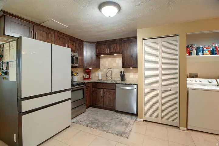 Wood-finish cabinetry, stainless steel appliances, tile flooring, and integrated laundry area