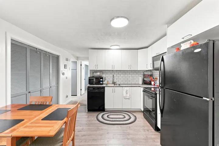 Kitchen featuring white cabinetry, subway tile backsplash, & black appliances. Updated in 2021