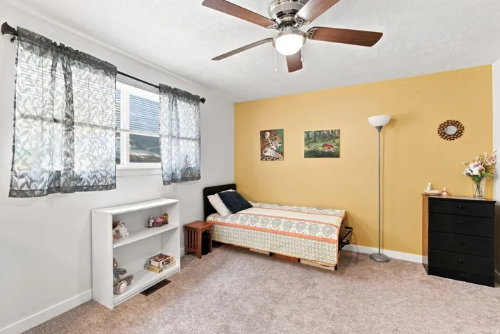 Recessed window with blinds, ceiling fan with light fixture, carpeted flooring, and a two-tone wall finish