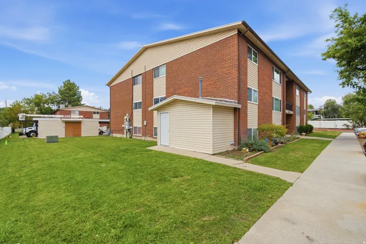 Brick and siding exterior with a concrete walkway & green space. Carport provides a storage area as well.