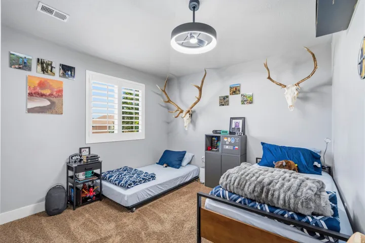 Carpeted room with a ceiling-mounted light fixture, a window with plantation shutters, and a corner cabinet