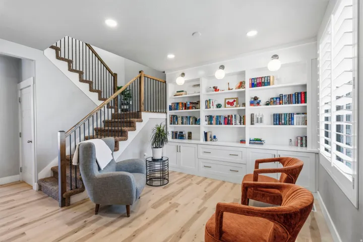 Custom built-in shelving with integrated cabinetry, wood-finish flooring, and a staircase featuring wood newel posts and metal balusters