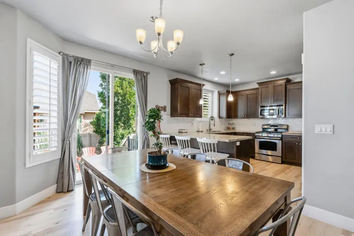 Wood-finish flooring, sliding glass door, white plantation shutters, dark wood cabinetry, and stainless steel appliances