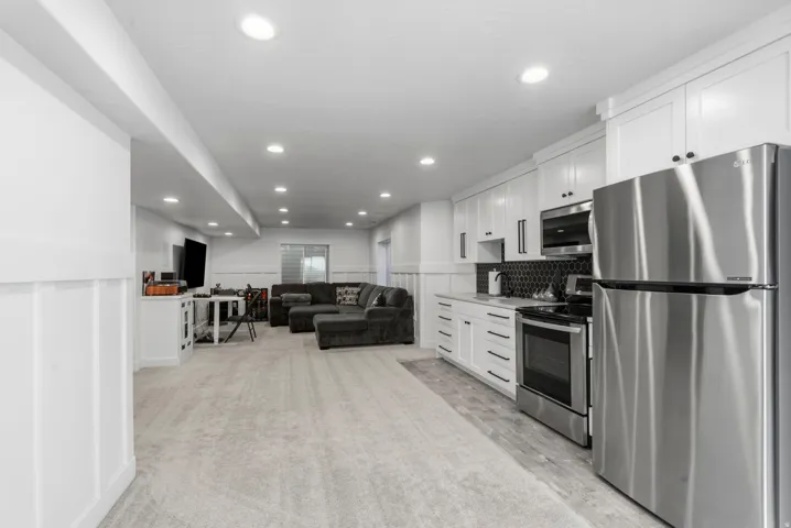Full kitchen with stainless steel appliances, white cabinetry, and a black hexagonal tile backsplash