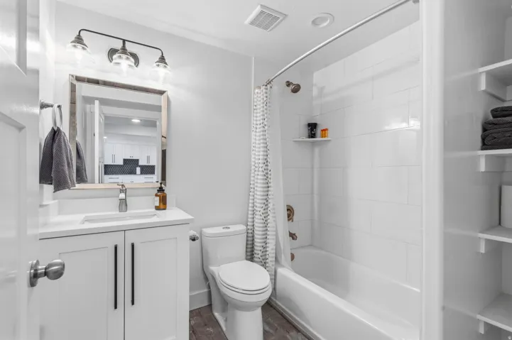 White vanity with integrated sink, modern black hardware, and a framed mirror
