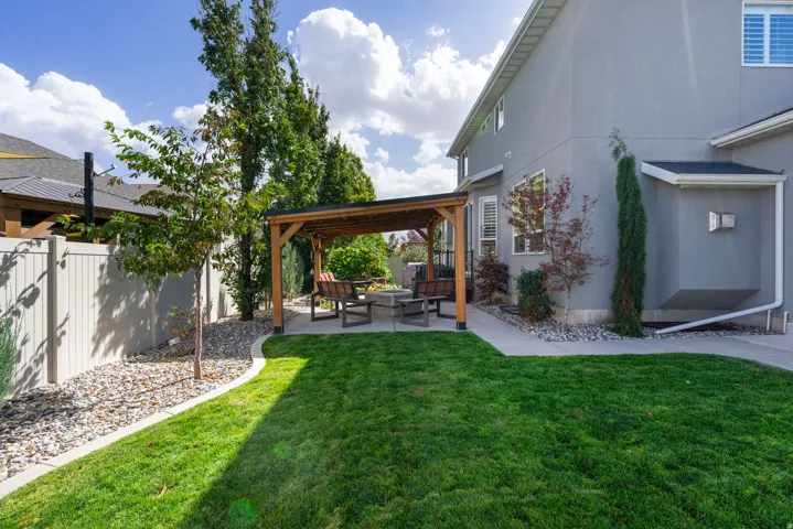 Expansive backyard featuring a lush lawn, concrete patio, and a wood pergola