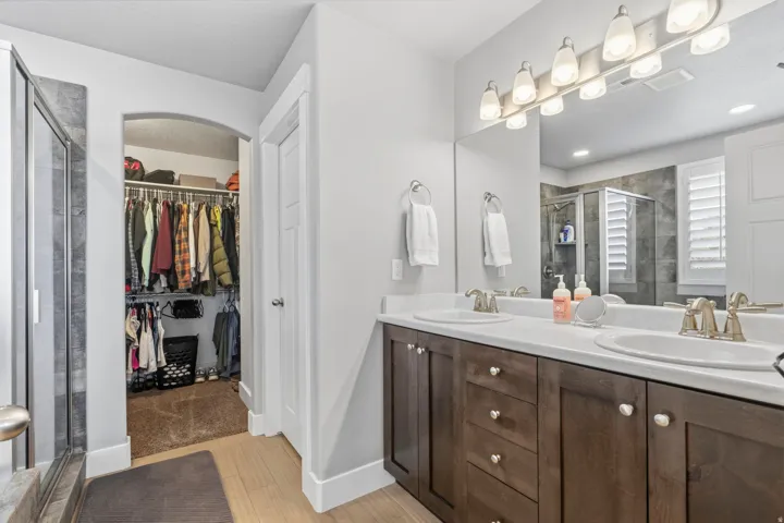 Double vanity with white countertops, wood-finish cabinetry, and brushed nickel fixtures