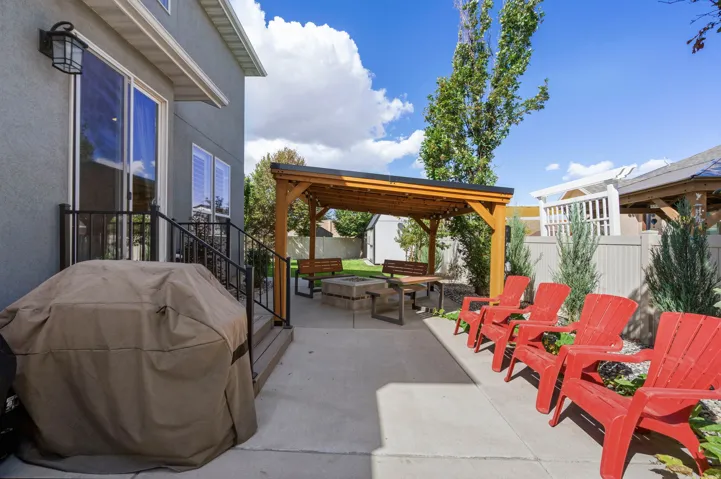 Outdoor patio with a wood pergola, built-in fire pit, and concrete hardscaping