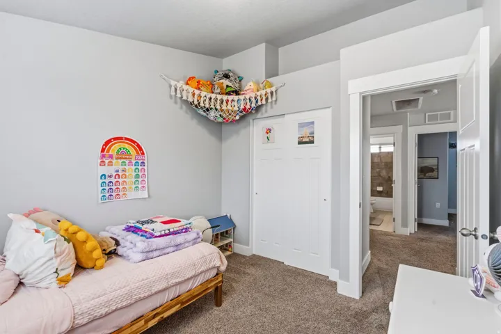 Carpeted bedroom featuring a wood-frame bed, white bi-fold closet doors, and light gray walls