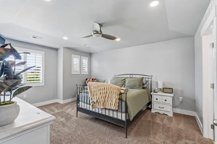 Recessed lighting, ceiling fan, white window shutters, and soft carpeting