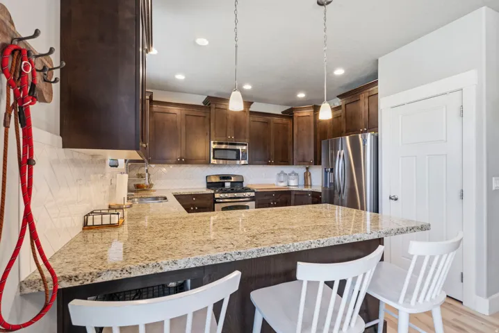 Kitchen featuring a breakfast bar with stone countertops, wood cabinetry, stainless steel appliances, and pendant lighting
