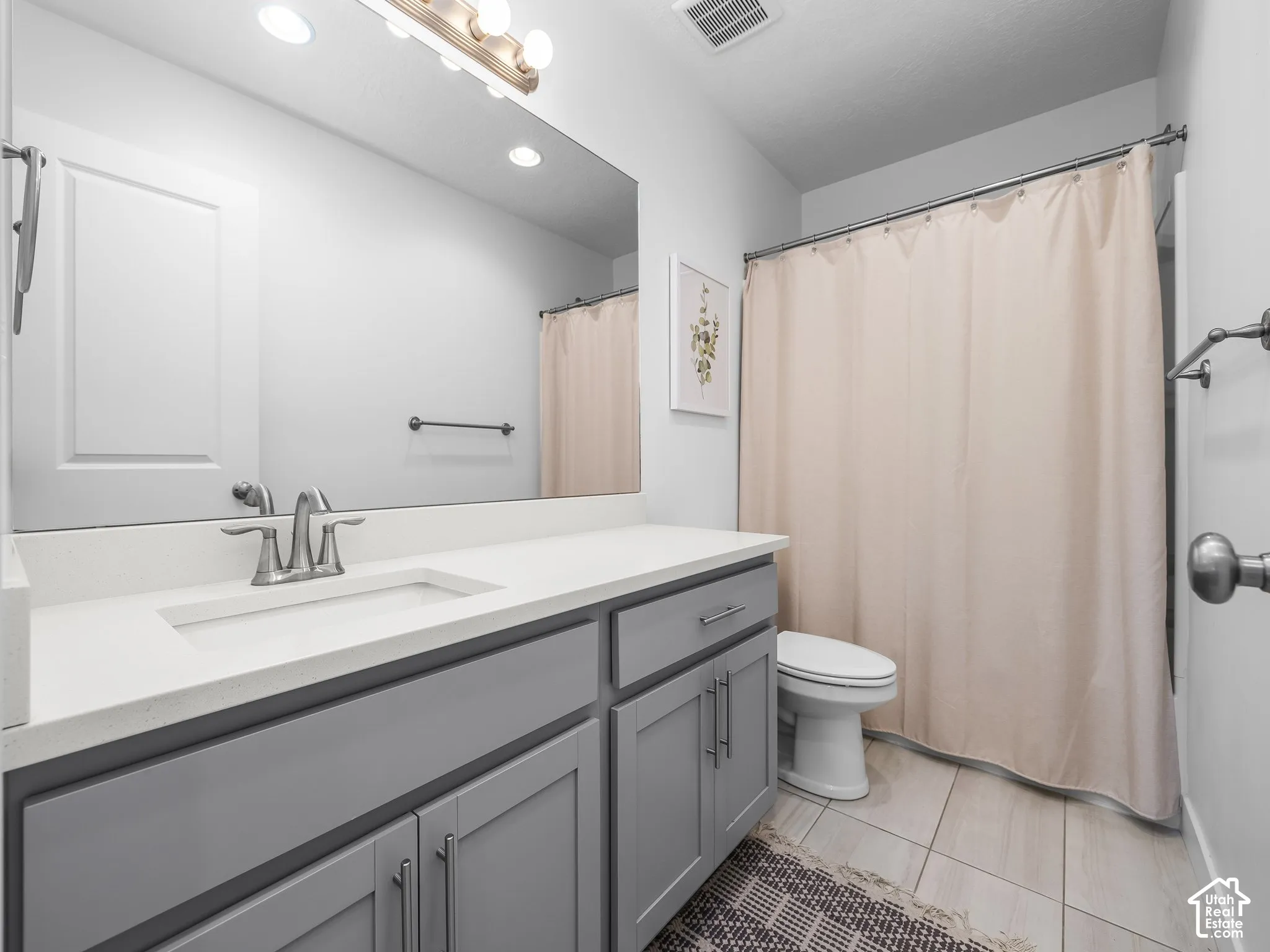 Vanity with light gray shaker-style cabinetry, white solid-surface countertop, and integrated sink